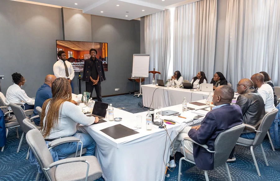Two presenters briefing a boardroom of seated officials, with a screen behind them reading Transforming Kenya's Education System with EDU AI.