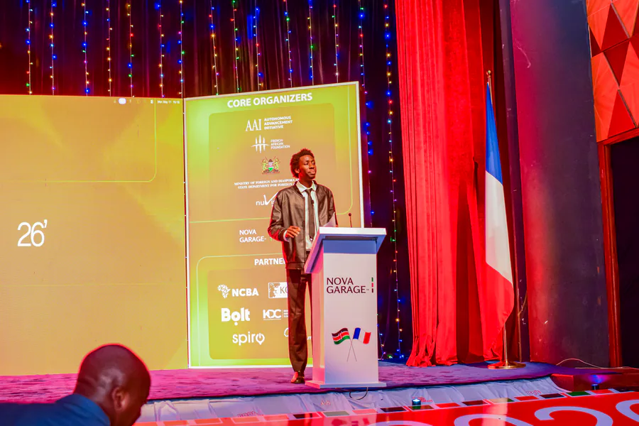 Eric Lunani speaking from the podium at the Nova Garage Summit 2026 in Nairobi, beside the French flag.